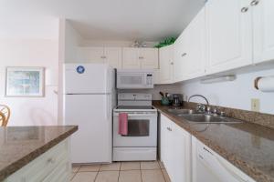uma cozinha branca com um lavatório e um frigorífico em Protea Condo em Kahuku