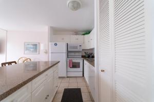 uma cozinha com armários brancos e um frigorífico branco em Protea Condo em Kahuku