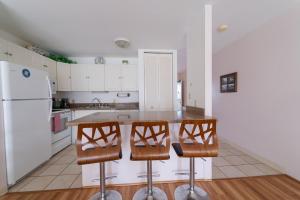 uma cozinha com um frigorífico branco, uma mesa e cadeiras em Protea Condo em Kahuku