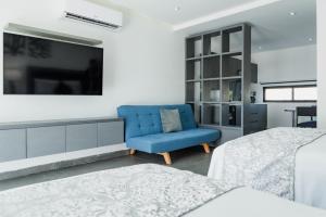 Un dormitorio con una silla azul y un televisor. en Dreams Apartments 1 Loft a 9 minutos de la playa, en Isla Mujeres