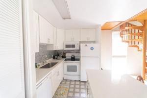 uma cozinha com armários brancos e electrodomésticos brancos em Turtle Bay Sage TA-097-866-3424-02 condo em Kahuku