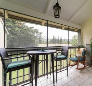 a balcony with a table and chairs and a large window at Aloha Nui Loa in Kahuku