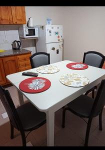 una mesa blanca con 4 sillas y una nevera blanca en Departamento Del Sol (Esquel-Chubut) en Esquel