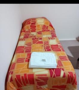 Una cama con colcha y una toalla. en Departamento Del Sol (Esquel-Chubut) en Esquel