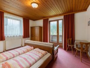 um quarto com uma cama, uma mesa e janelas em Ferienwohnungen-LIPPENHOF em Sankt Jakob in Defereggen