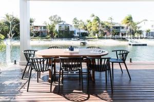 a wooden table and chairs on a deck next to the water at The River House includes a private beach jetty and pool in Noosa Heads