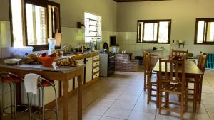 a kitchen with a counter and a table and chairs at Casa de Campo - Sítio da tia Vera in Maquiné