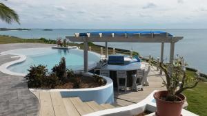 una piscina con una mesa y una pérgola junto al océano en Neptune Cove home en Alice Town