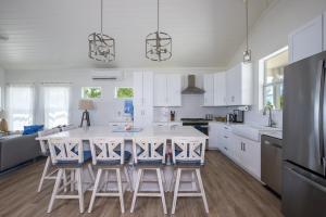 una cocina con armarios blancos y una mesa con taburetes en Lavender Beach House home, en James Cistern