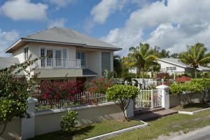 una casa con una valla blanca y palmeras en Long Island Breeze Compound home en Nassau