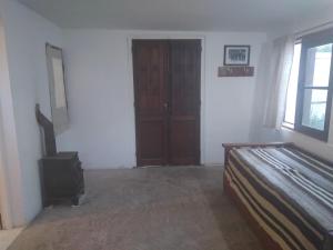 1 dormitorio con cama, ventana y puerta en La Posta San Fernando en Villa Allende