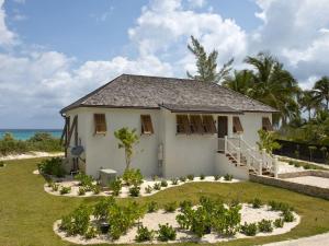 a white house with a garden in front of the ocean at French Leave South Beach Dogtrot Villa villa in Governorʼs Harbour