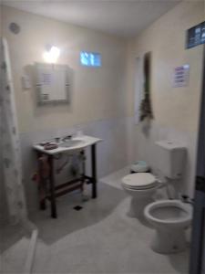y baño con aseo blanco y lavamanos. en La Posta San Fernando en Villa Allende