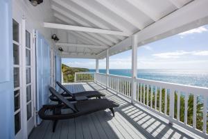 - une terrasse couverte avec 2 chaises et l'océan dans l'établissement Palm Bluff cottage, à Gregory Town