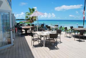 um pátio exterior com mesas e cadeiras e o oceano em Cocodimama Resort Hotel Room em James Cistern