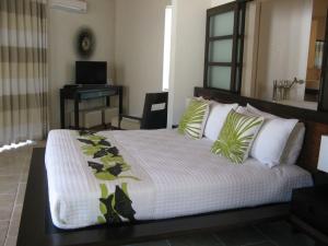 Un dormitorio con una cama grande con almohadas verdes y blancas en Sky Beach Club Bungalow cabin, en Governorʼs Harbour