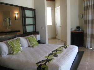 1 dormitorio con 1 cama grande con almohadas verdes en Sky Beach Club Bungalow cabin, en Governorʼs Harbour