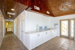 a kitchen with white cabinets and a wooden ceiling at Sand Dollar at Ten Bay Beach home in Savannah Sound