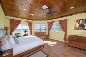 a bedroom with a bed and a couch and windows at Sand Dollar at Ten Bay Beach home in Savannah Sound