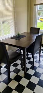 a dining room table with chairs and a checkered floor at The Nurses Home Guesthouse - Reefton in Reefton