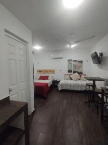 1 dormitorio con 2 camas, mesa y puerta en Estudio a 15 min caminando de la terminal de autobuses ADO, en Cancún