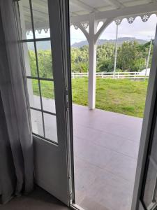 een open deur naar een veranda met uitzicht op een veld bij Maison ika in Le François