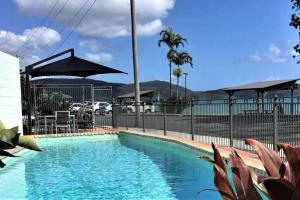 a large swimming pool with a fence and an umbrella at Little Coastal Haven apartment with a pool! in Cannonvale