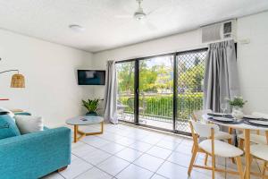 a living room with a blue couch and a table at Little Coastal Haven apartment with a pool! in Cannonvale