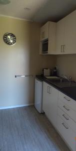 uma pequena cozinha com armários brancos e um lavatório em Nangari Studio Unit em Alexandra