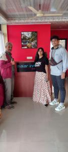 three people standing in a room with a red wall at Malar inn in Port Blair