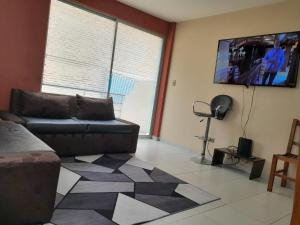 sala de estar con sofá y TV de pantalla plana en DEPARTAMENTO COMODO DUPLEX Zona Norte, en Cochabamba