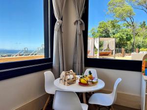 a table and chairs in a room with two windows at Chateau Laghetto Collection in Gramado