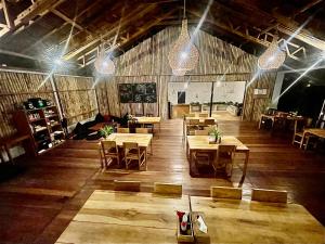 ブナケンにある3WILL Bunaken Dive Resortの木製のテーブルと椅子、照明が備わるレストラン