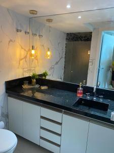 uma casa de banho com um lavatório e um espelho em Belo apartamento Ondina Apart em Salvador