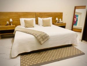 una camera da letto con un grande letto con lenzuola e cuscini bianchi di Vía Real Hotel Boutique a Atotonilco el Alto
