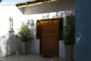 ein Haus mit einer Holztür und zwei Topfpflanzen in der Unterkunft Casa Ramal in Ciudad Lujan de Cuyo