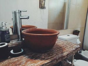 baño con un gran tazón de cobre en una encimera de madera en Casa Ramal en Luján de Cuyo