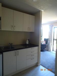 a kitchen with white cabinets and a sink at Nangari Studio Unit in Alexandra