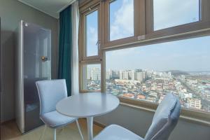 全州市にあるJeonju Signature Hotel&Residenceのテーブルと椅子2脚、窓が備わる客室です。