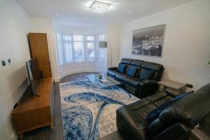 a living room with a leather couch and a table at Newly Refurbished Modern 4 Bed Detached House ! in Oxford