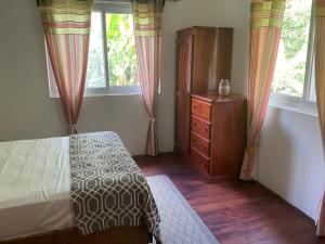 um quarto com uma cama, uma cómoda e janelas em Pretty house Bastimentos Bocas del toro em Bastimentos