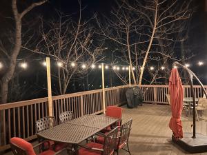 een tafel en stoelen op een terras met verlichting bij One of a Kind Rustic Log Cabin near Bryce Resort - Large Game Room - Fire Pit - Large Deck - BBQ in Basye