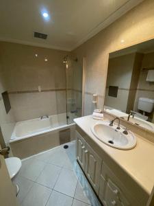 a bathroom with a sink and a tub and a toilet at El Lago Waters Resort in The Entrance