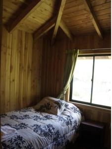 ein Schlafzimmer mit einem Bett in einem Zimmer mit einem Fenster in der Unterkunft Cabañas-apartamentos Borde Río in Neltume