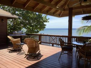 a wooden deck with chairs and tables and the ocean at Reef Beach House - 2 Bedrooms and studio in Sandy Bay