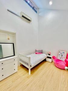 Habitación para bebés con cuna, TV y cama en The Palace Guest House, Seri Gading Batu Pahat, en Batu Pahat