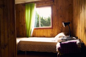 1 dormitorio con 1 cama y una ventana con cortinas verdes en CABAÑA AZUL Y VERDE, en Ancud