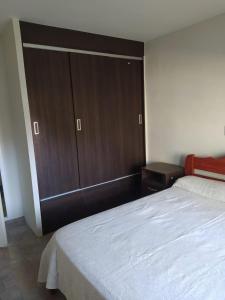 1 dormitorio con 1 cama grande y armario de madera en Casa Rural La Serena Cabaña en San Rafael