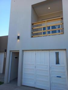 uma garagem com duas portas brancas e uma varanda em Como en casa em Tres Arroyos