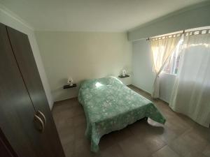 um quarto com um cobertor verde no chão e uma janela em Como en casa em Tres Arroyos